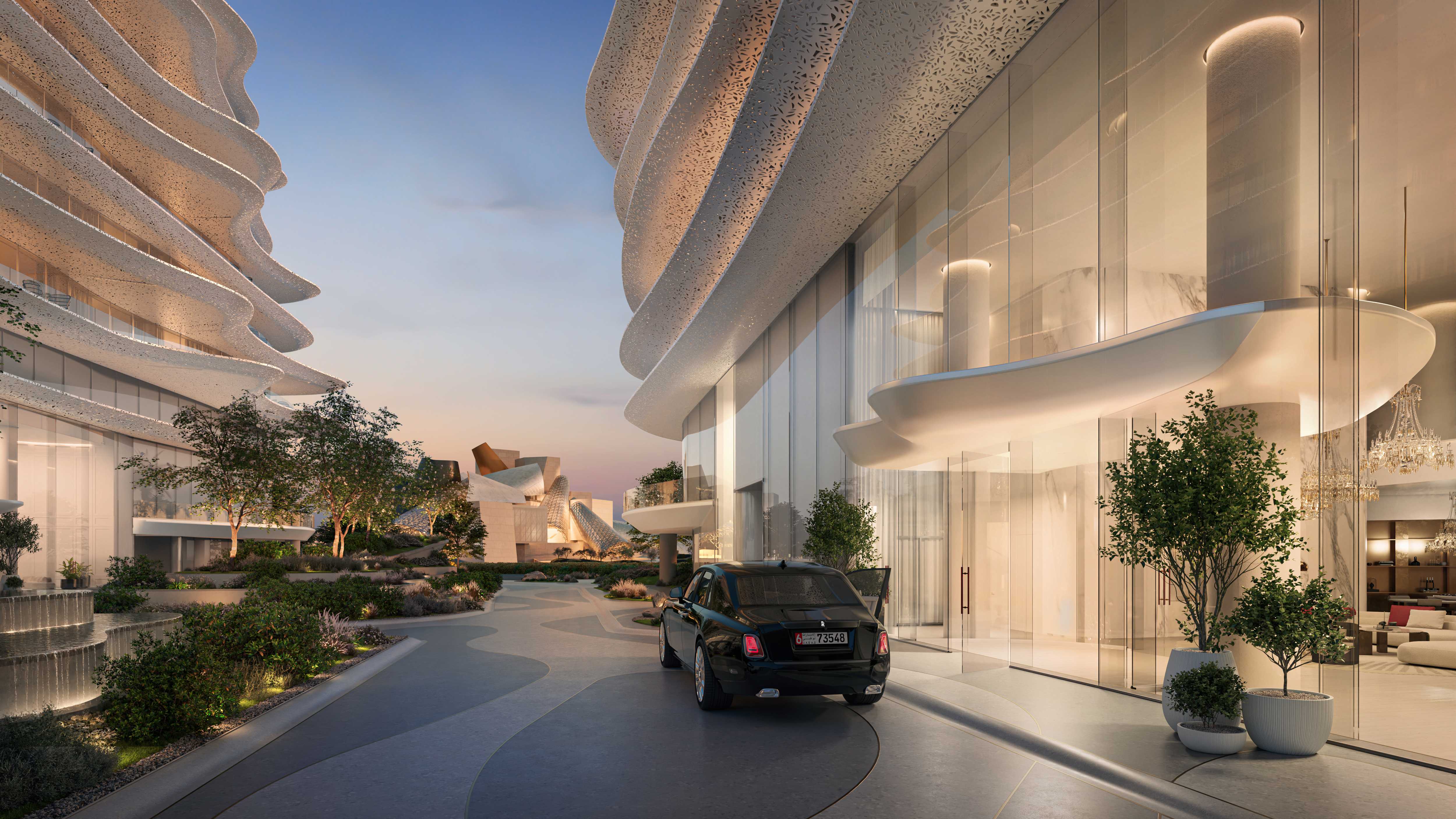 Twilight entrance drop-off at Baccarat Residences Saadiyat, with a black luxury car parked beneath the building's sculptural perforated overhang, landscaped gardens and a water feature nearby, and the Guggenheim Abu Dhabi visible in the background.