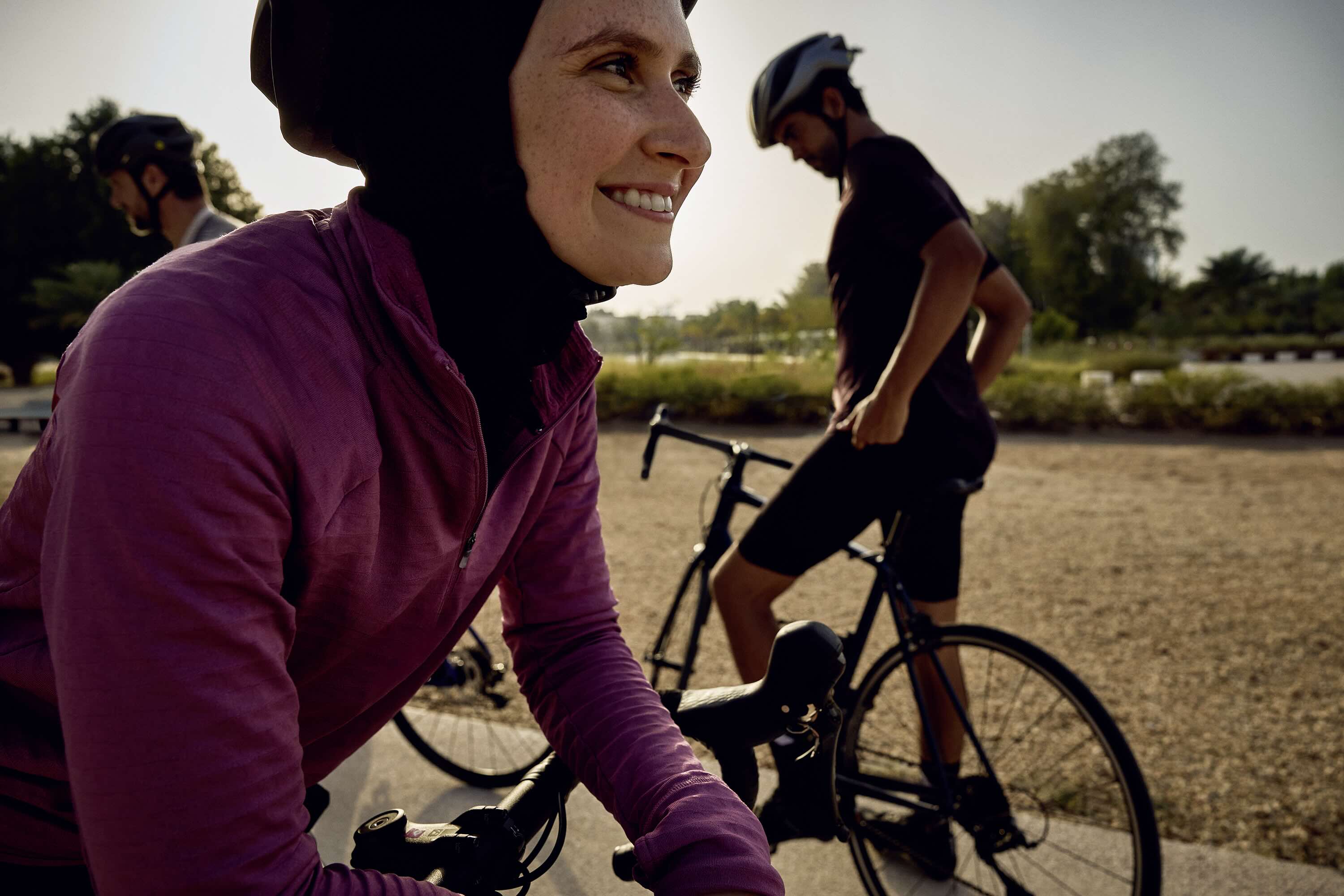 Residents cycling outdoors in the Athlon community, with a smiling woman in cycling gear in the foreground