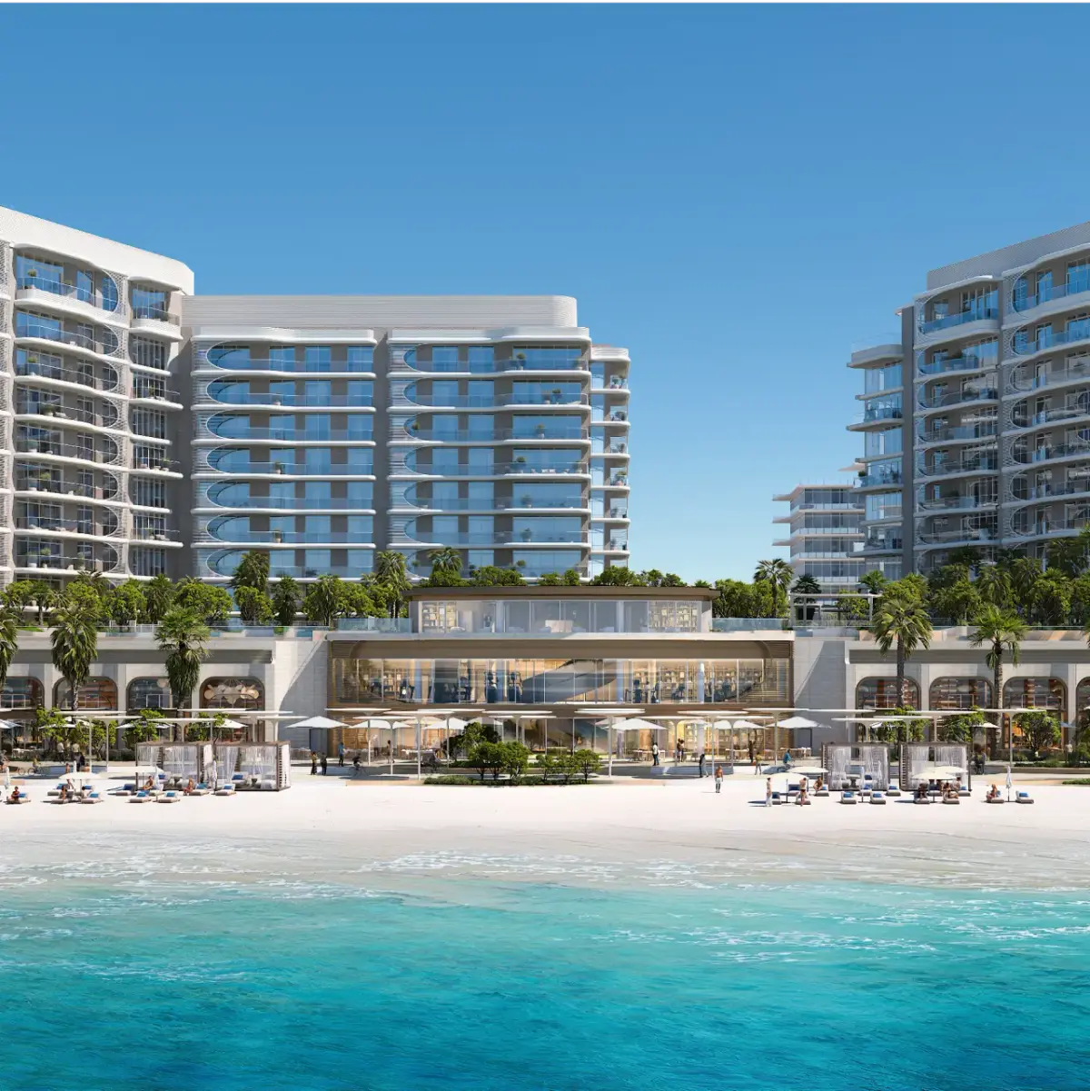 View from the water of Fahid Beach Terraces high-rise residential buildings with curved white balconies, a beachfront clubhouse with retail arcades below, and a private beach with sun loungers, cabanas, and umbrellas along turquoise waters.
